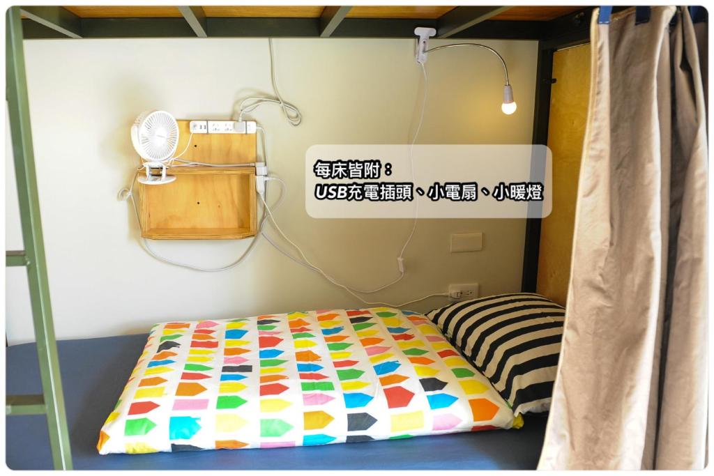 Una habitación con una cama en una habitación con un cartel en Taitung Ohana Sky Hostel, en Taitung