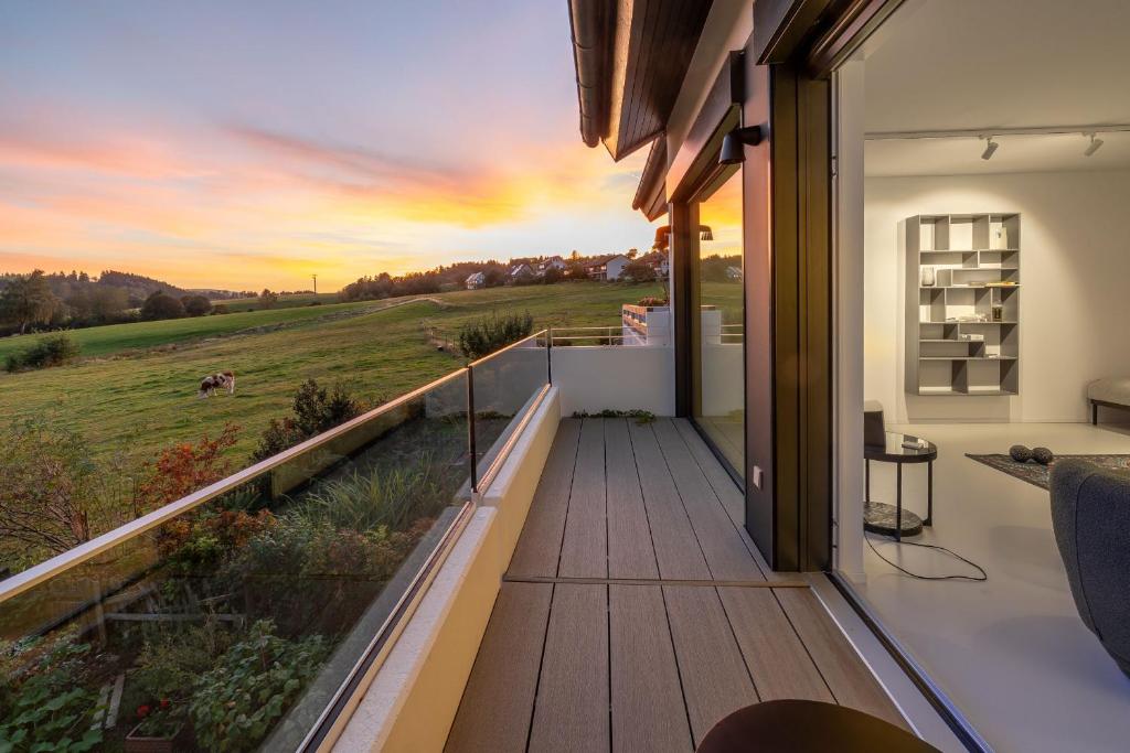 a house with a balcony with a view of a field at Ferienhaus Daheim in Sankt Peter