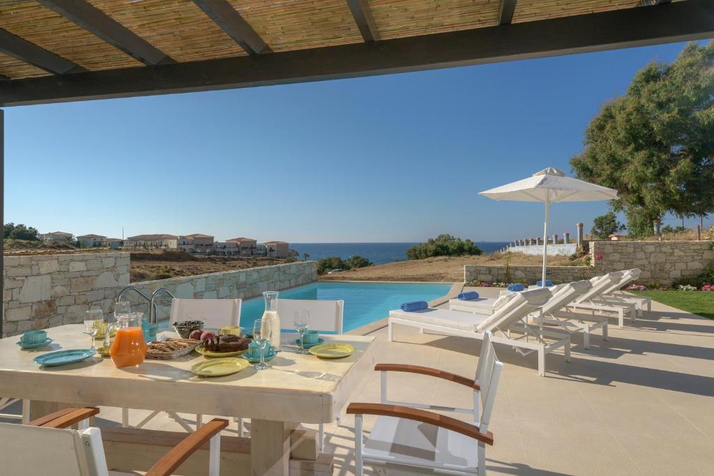 a white table and chairs with a view of a pool at Lygaries Villas in Panormos Rethymno