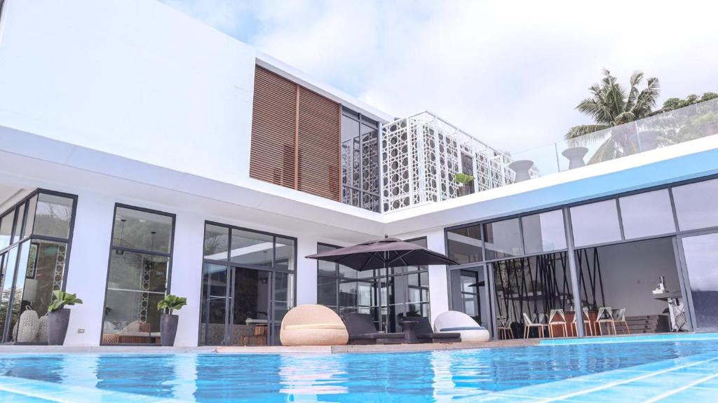 een huis met een zwembad en een gebouw bij Sisid Anilao Resort in Mabini