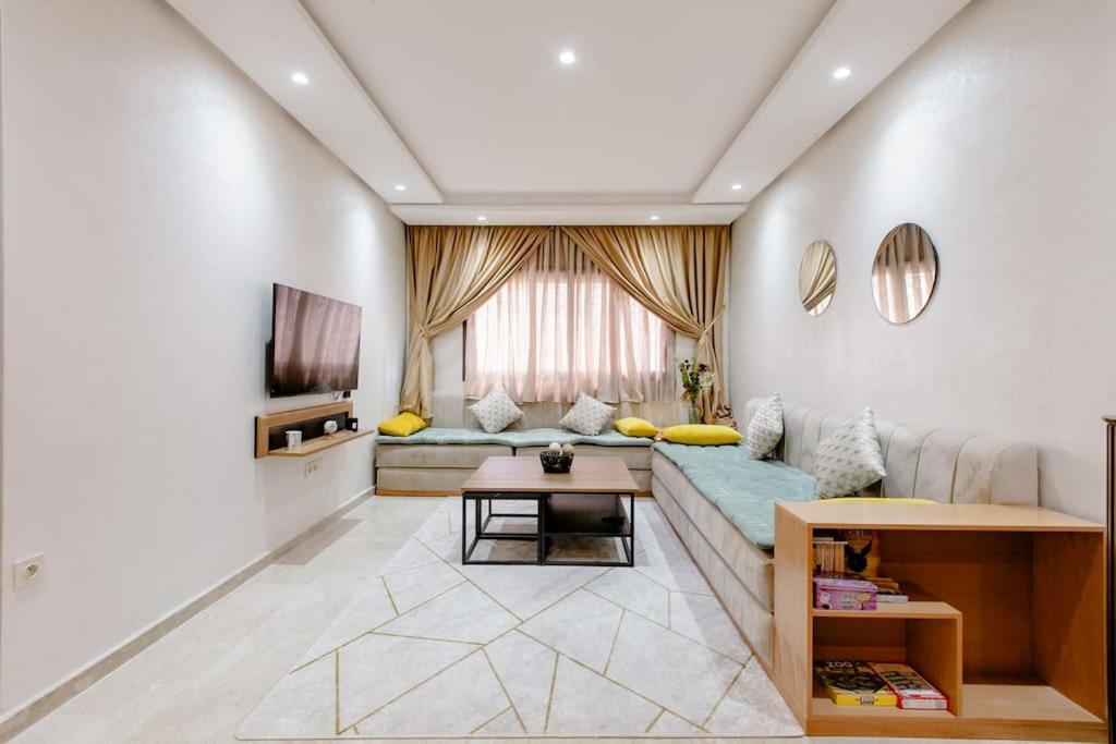 uma sala de estar com um sofá e uma televisão em Appartement résidence Marrakech haut standing piscine em Marrakech