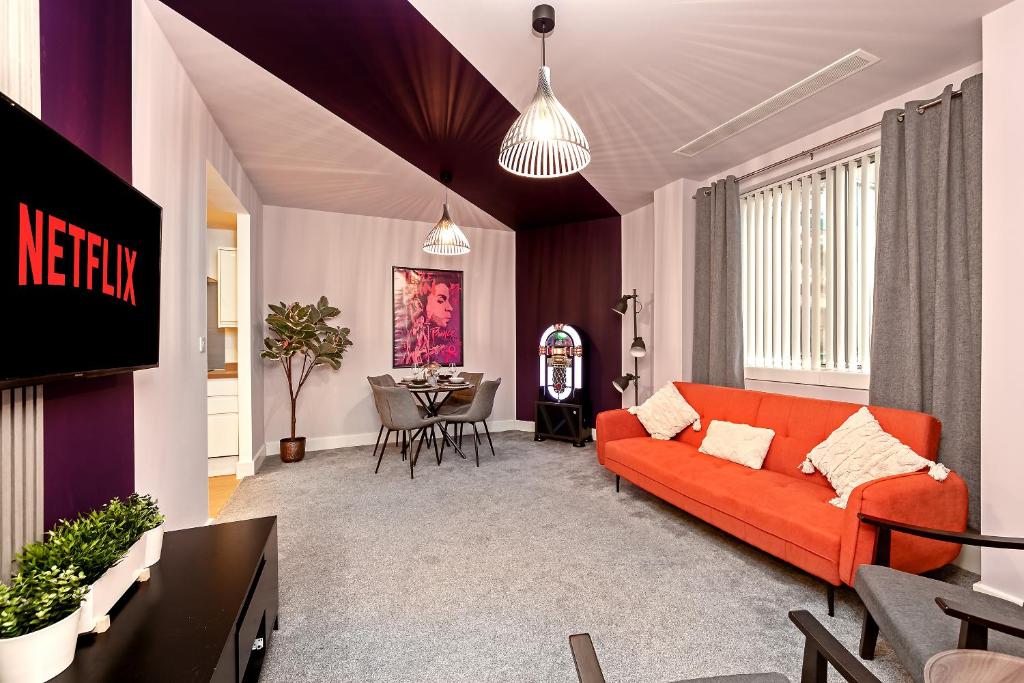 a living room with an orange couch and a table at PRIME City Centre Location, THE JUKE BOX SUITE, Secure Gated FREE Parking Space, Unique STYLISH Apartment, Two Bathrooms in Milton Keynes