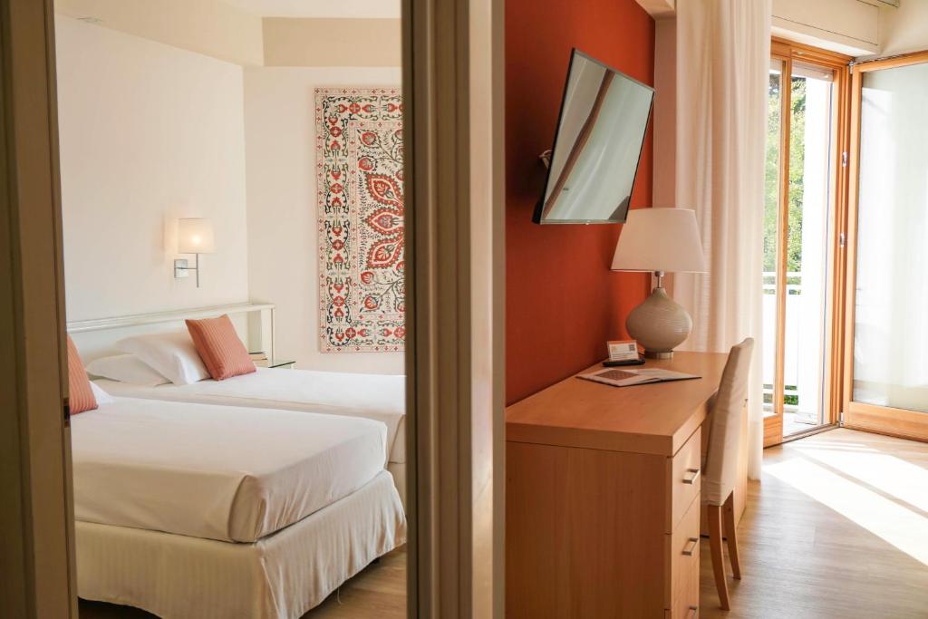 una camera con 2 letti, una scrivania e una finestra di Art&Park Hotel Union Lido a Cavallino-Treporti