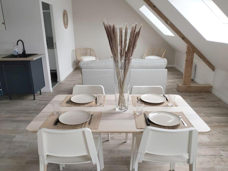 a dining table with white chairs and a vase at Appartement « La brise de Mer » - 50m de la plage in Bray-Dunes
