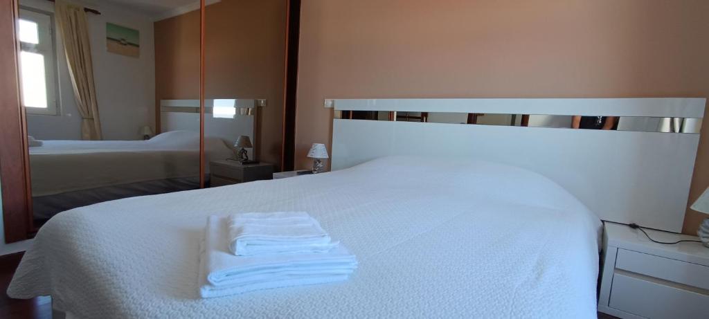 Un dormitorio con una cama blanca con una toalla. en Reis Magos Beach Caniço Sea line Apartment, en Caniço