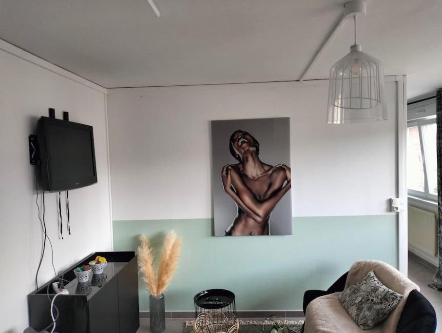 a living room with a painting of a man on the wall at Petit cocon sur Coudekerque-Branche in Coudekerque-Branche