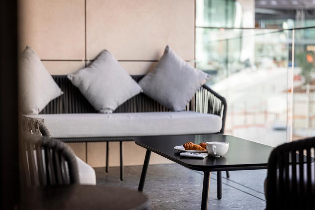 a couch with pillows and a table with a cup of coffee at The Londoner Hotel St. Julian's in St. Julianʼs
