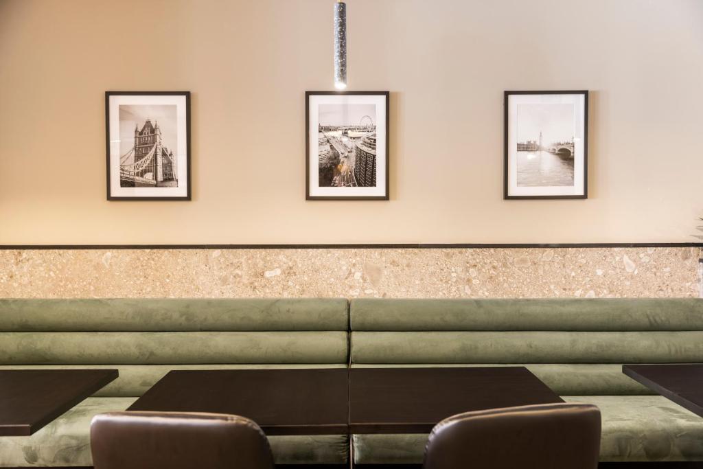 a waiting room with a couch and four pictures on the wall at The Londoner Hotel St. Julian's in St. Julianʼs