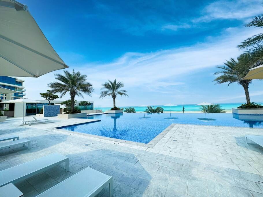 uma piscina com palmeiras e o oceano em Soul Beach Relaxation! 112MB1 em Abu Dhabi