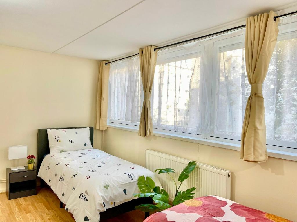 um quarto com uma cama e duas janelas em 3BR Central London close to Piccadily Line em Londres