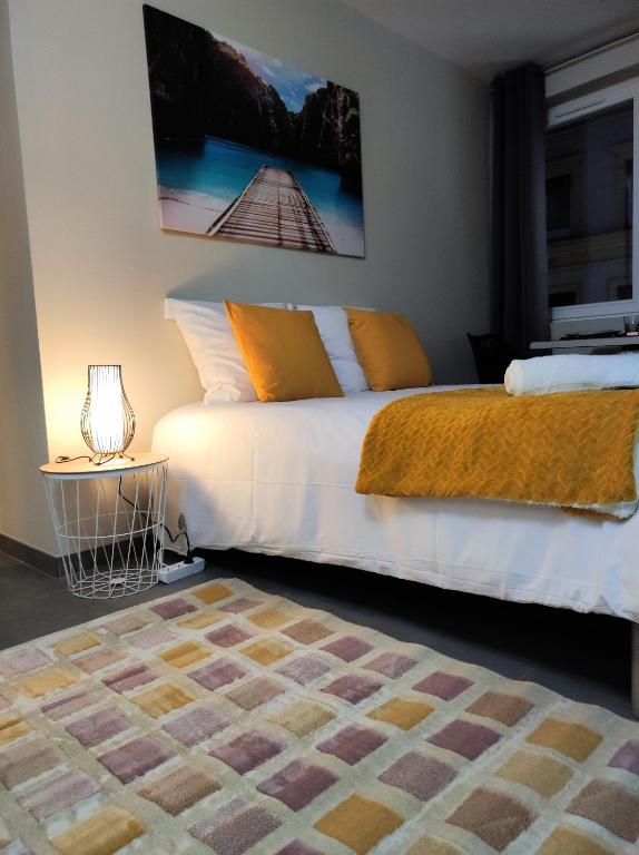 - une chambre avec un lit blanc et une couverture orange dans l'établissement Le LUX 31, à Thionville