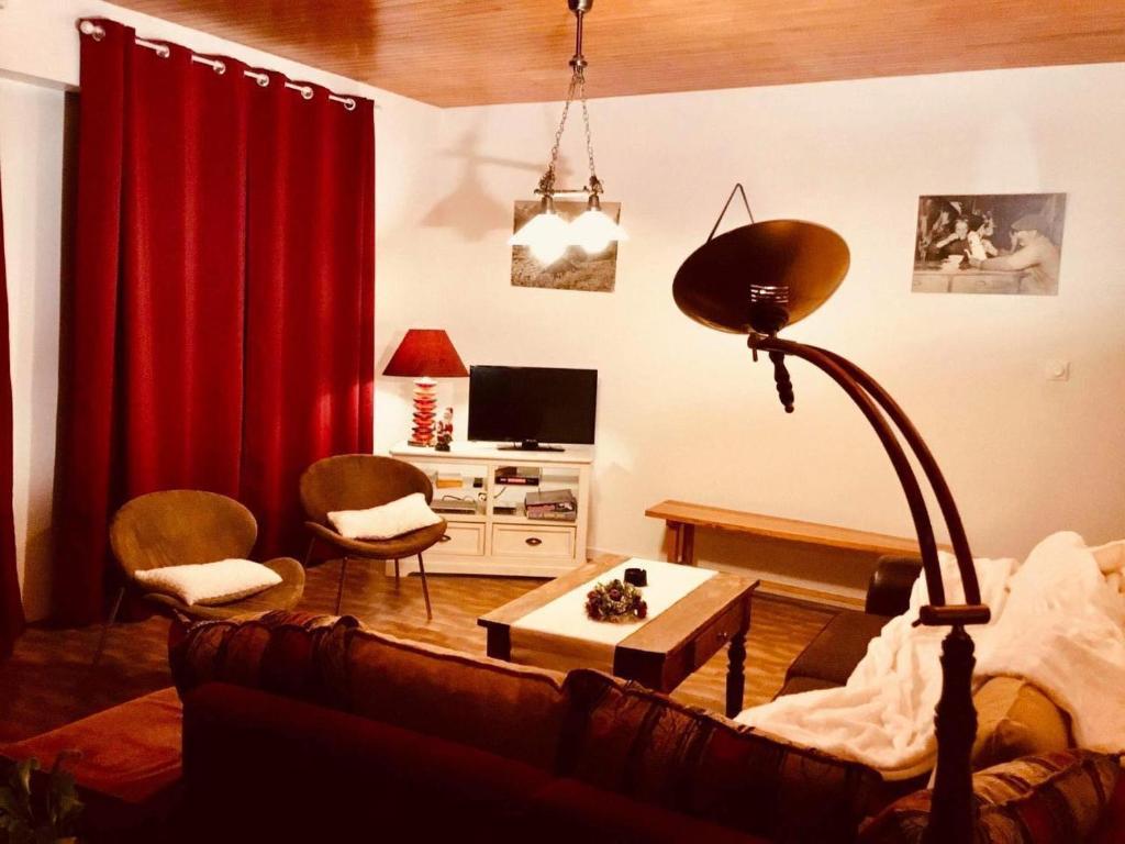 a living room with a couch and a red curtain at La Maison de Marie « Le Rocher » in Saint-Bonnet-en-Champsaur