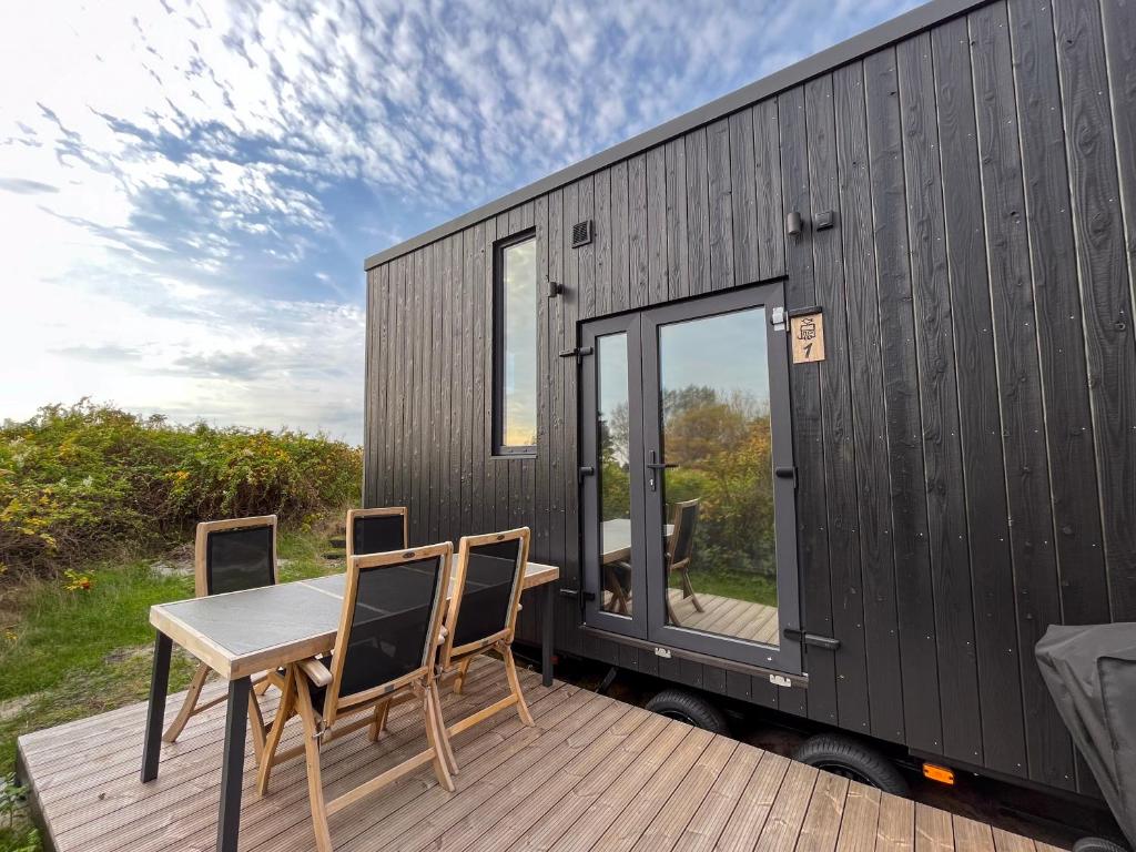 una pequeña casa negra con una mesa y sillas en una terraza en Tiny Seaside - Skarrev en Åbenrå