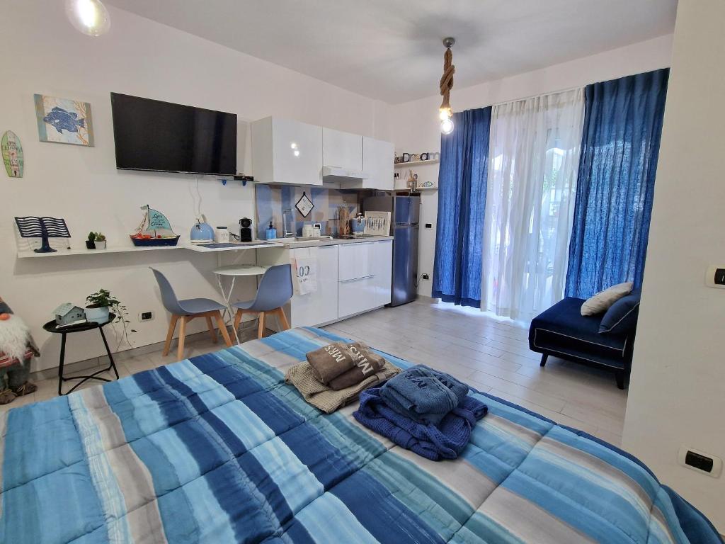 a bedroom with a blue bed and a kitchen at Alloggio in residence con pontile privato e accesso diretto al mare in Santa Marinella