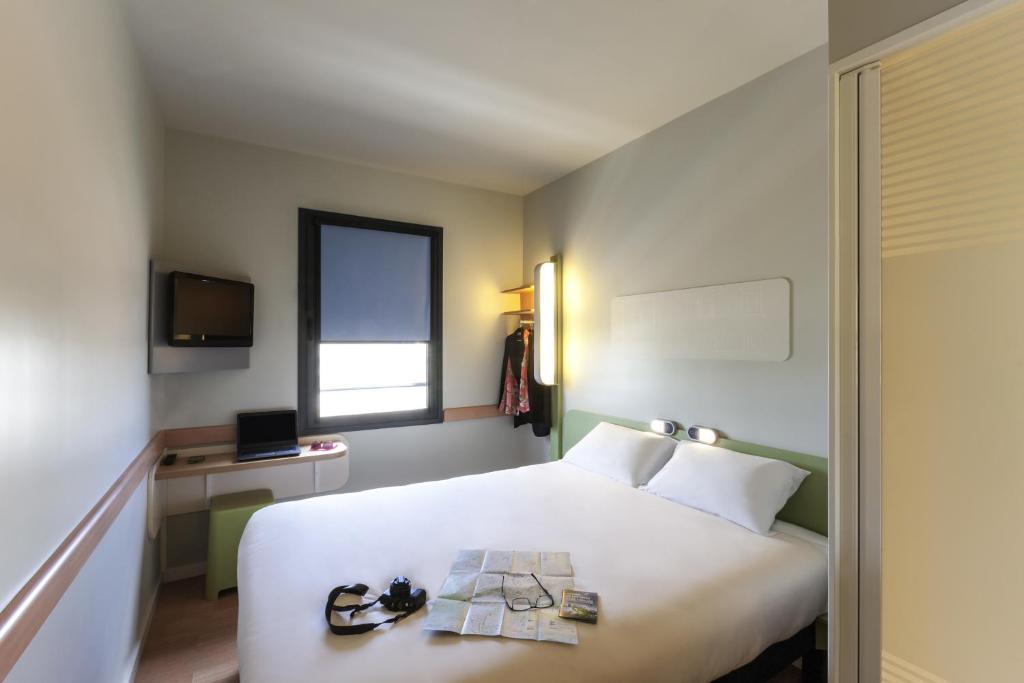 a hotel room with a white bed and a window at Ibis Budget Valencia Alcasser in Silla