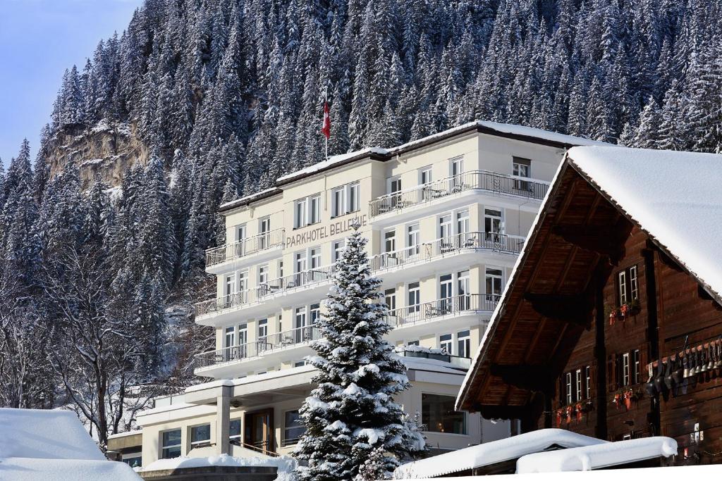 a building with a christmas tree in front of a mountain at Bellevue Parkhotel & Spa - Relais & Châteaux in Adelboden