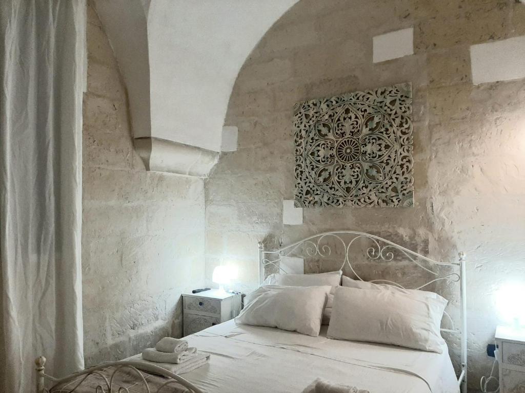 um quarto com uma cama branca e uma parede de pedra em Il Vico em Lecce