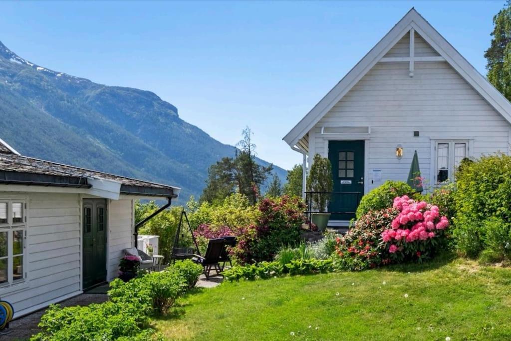 una pequeña casa blanca con un patio con flores en Nydelig lite hus med egen vedfyrt baksteovn. en Kaupanger