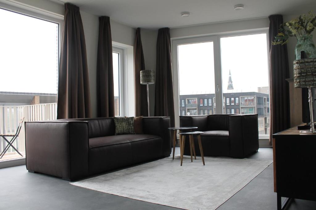 a living room with black furniture and large windows at Trompstraat Eindhoven in Eindhoven