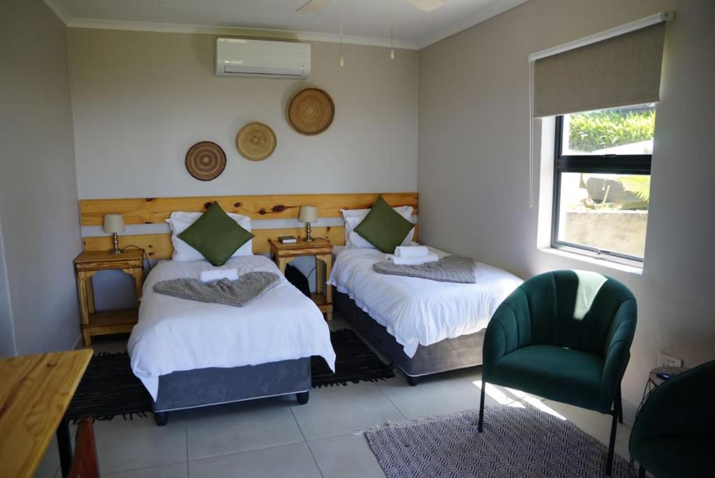 a bedroom with two beds and a chair and a window at Nabana Lodge in Hazyview