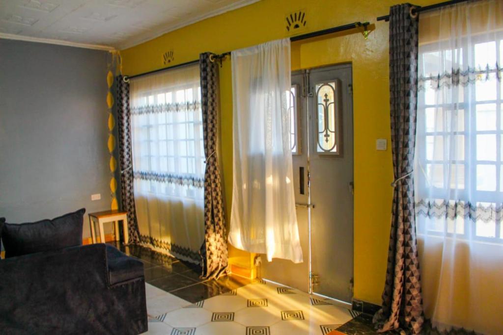 a living room with yellow walls and windows at Hotfoot Homestays in Kiganjo