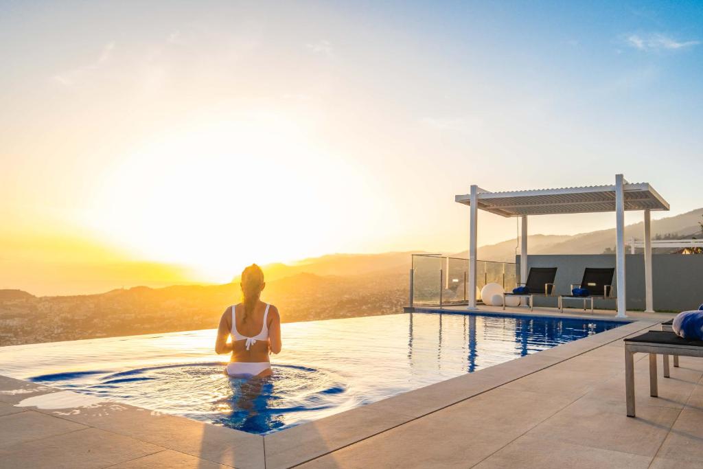 Una donna seduta in piscina sopra una casa di Villa Boa Nova Preta by LovelyStay a Funchal