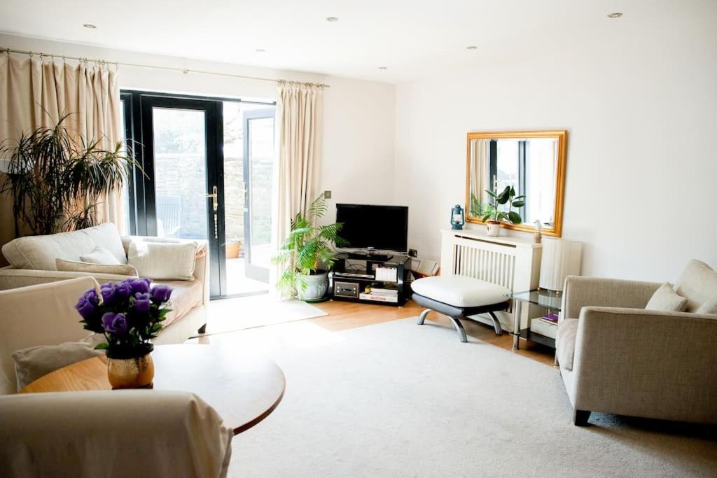 a living room with couches and a table and a tv at Central Spacious Ground Floor Flat with Courtyard in Kingsbridge