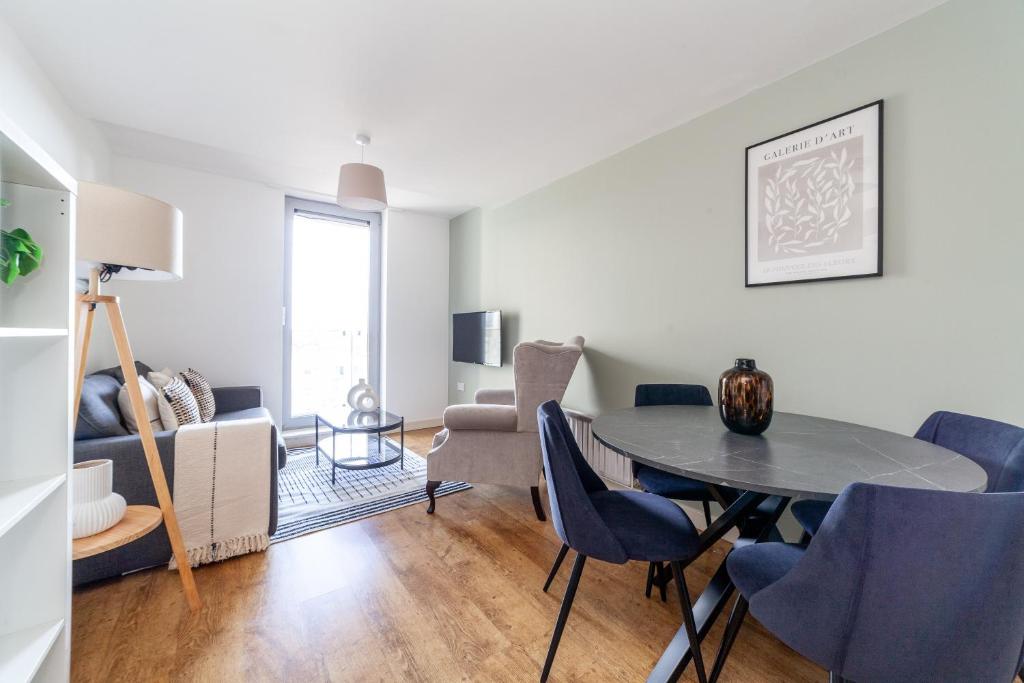 een woonkamer met een tafel en blauwe stoelen bij The Stratford Apartments in Londen