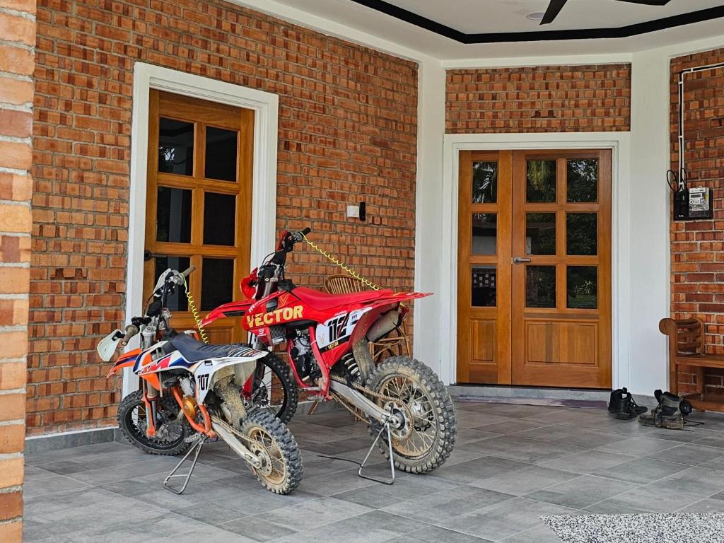 una moto rossa sterrata parcheggiata accanto a una casa di mattoni di BRIK 'N BATA a Batang Berjuntai