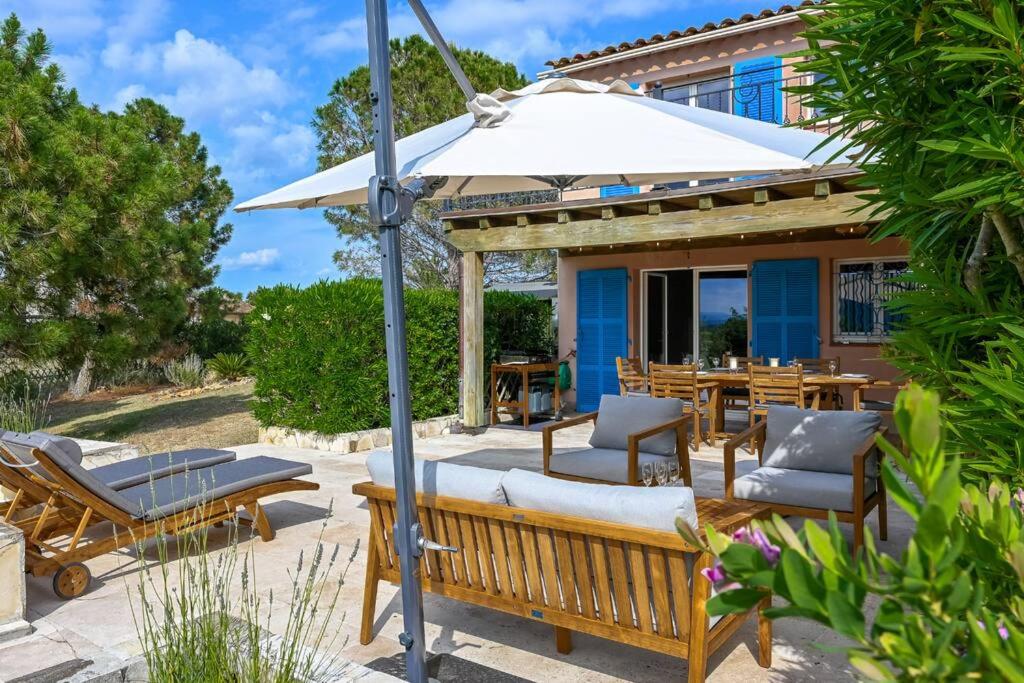eine Terrasse mit Bänken und einem Sonnenschirm in der Unterkunft Esprit du Sud Les 4 Mousquetaires in Roquebrune-sur-Argens