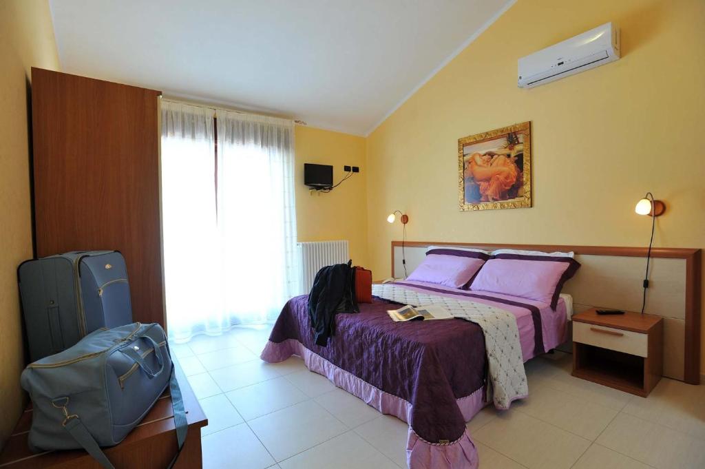 una camera d'albergo con due letti e una valigia di B&B Casa Augello a San Giovanni Rotondo