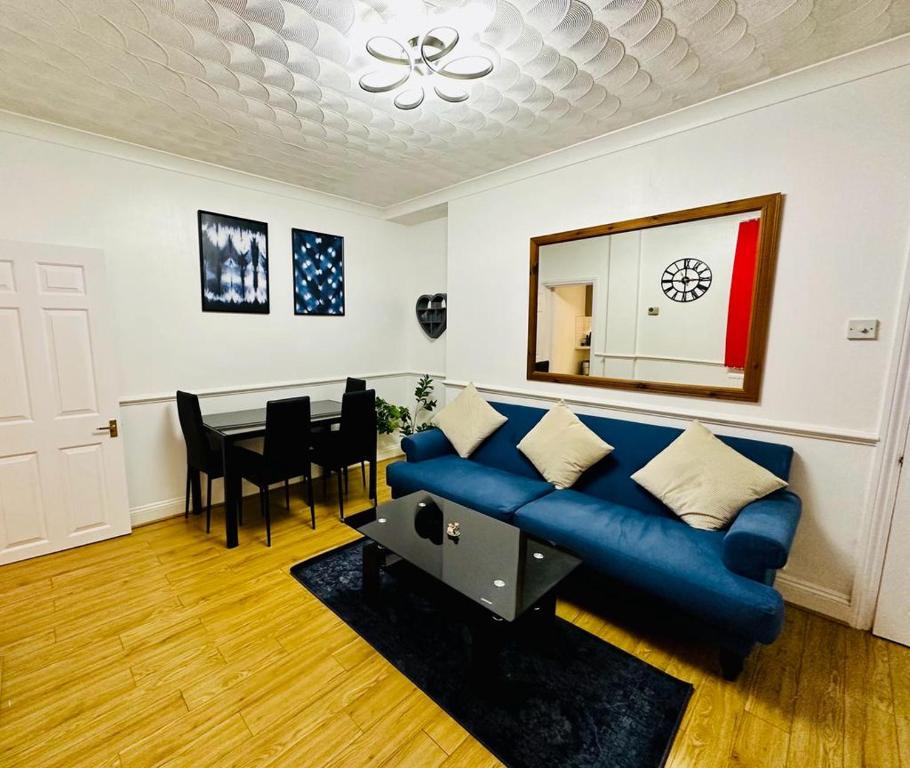 a living room with a blue couch and a table at Cosy 3 Bed House - Reading Cent. Free Parking in Reading