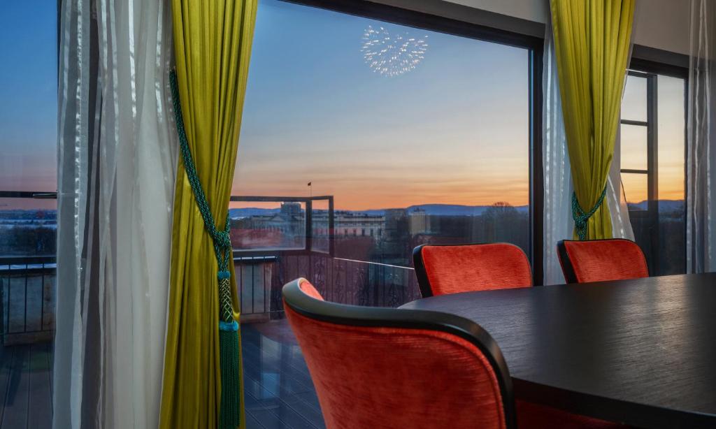une table et des chaises dans une chambre avec une grande fenêtre dans l'établissement Thon Hotel Slottsparken, à Oslo