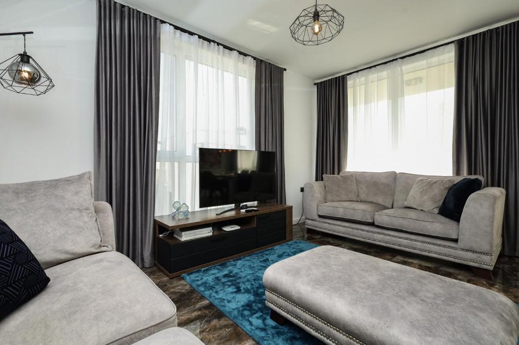 ein Wohnzimmer mit einem Sofa und einem TV in der Unterkunft Skarabey Park Apartment Sarafovo in Burgas City