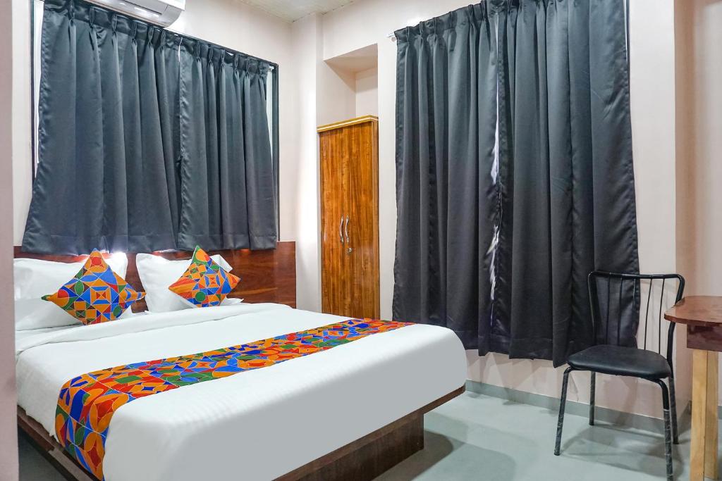 a bedroom with a bed with black curtains and a chair at FabHotel Skyline I in Méribel Village