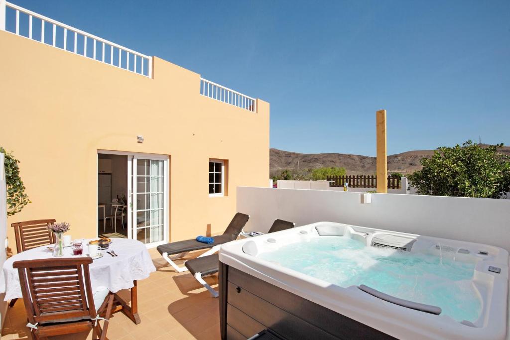 patio con tavolo, sedie e vasca idromassaggio. di Apartamento El Naranjo con jacuzzi a Tarajalejo