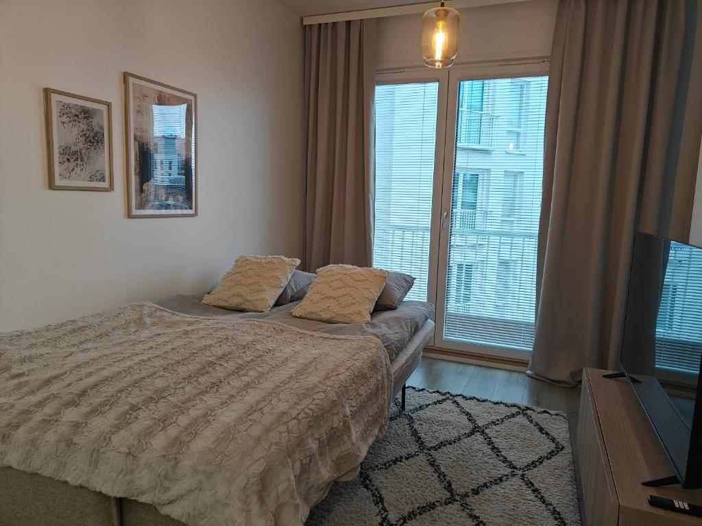 a bedroom with a bed and a tv and windows at Lapland Arctic Apartments in Rovaniemi