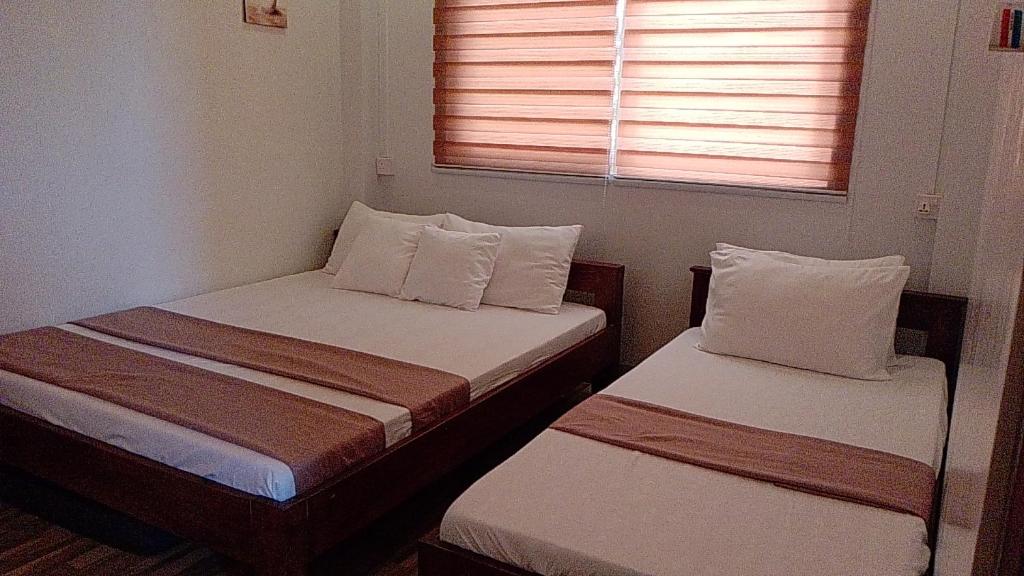 2 camas en una habitación pequeña con ventana en FNT Transient House en Alaminos