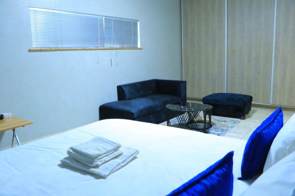 Habitación con cama, 2 sillas y ventana en La Maison Guesthouse, en Thohoyandou