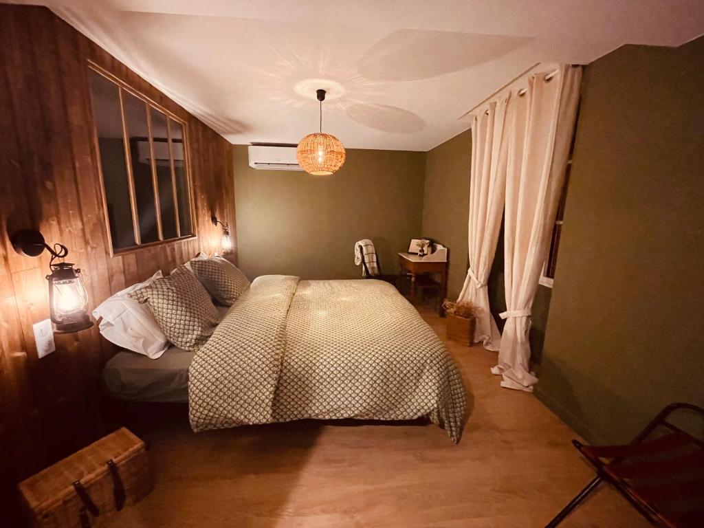 a bedroom with a bed with a comforter on it at LA CABANE AFFRANCHIE in Moussy