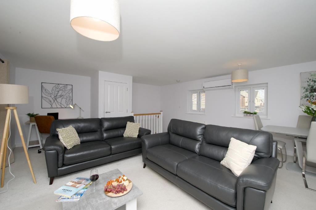 uma sala de estar com um sofá de couro preto e uma mesa em Fairfields Coach House em Stony Stratford