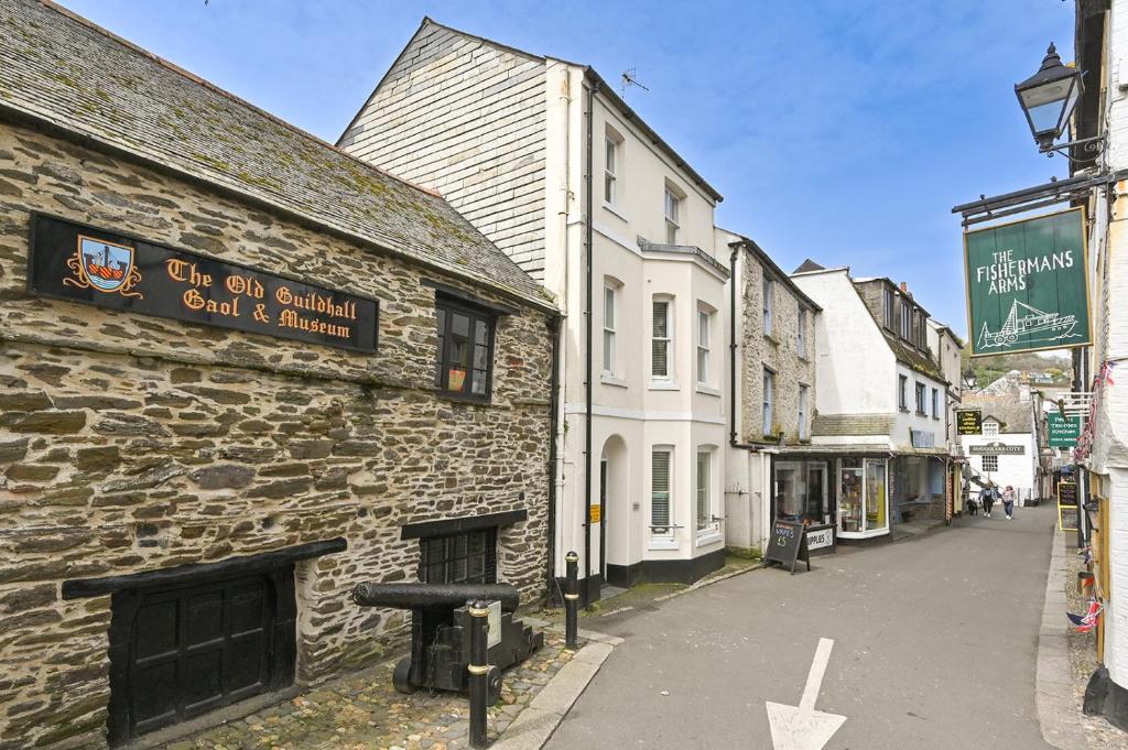 an old stone building with a sign on the side of a street at Captain's House Looe in Looe