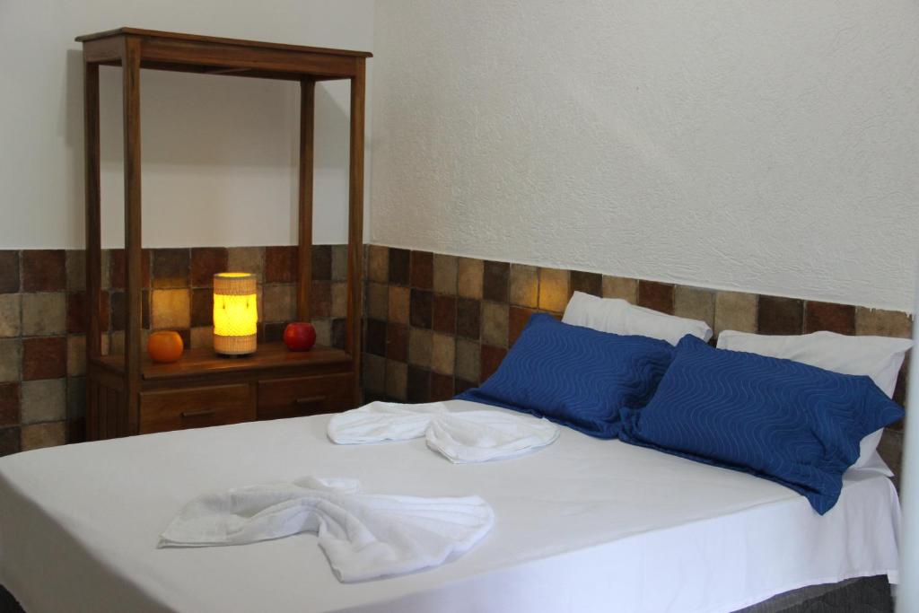 a bedroom with a bed with blue pillows and a mirror at Casa Mãe da Lua in Arraial d'Ajuda