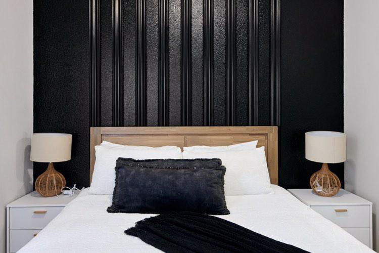 a bedroom with a bed with a black headboard and two lamps at Sunrise Rivonia One Bed in Johannesburg