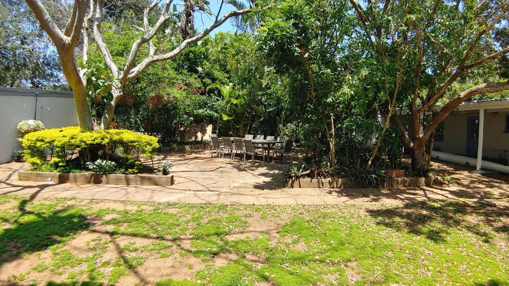 a patio with chairs and trees in a yard at The Beach Bungalows in Zinkwazi Beach