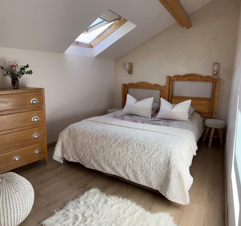 a bedroom with a bed and a dresser and a window at Gite Au Grenier Cosy in Lor