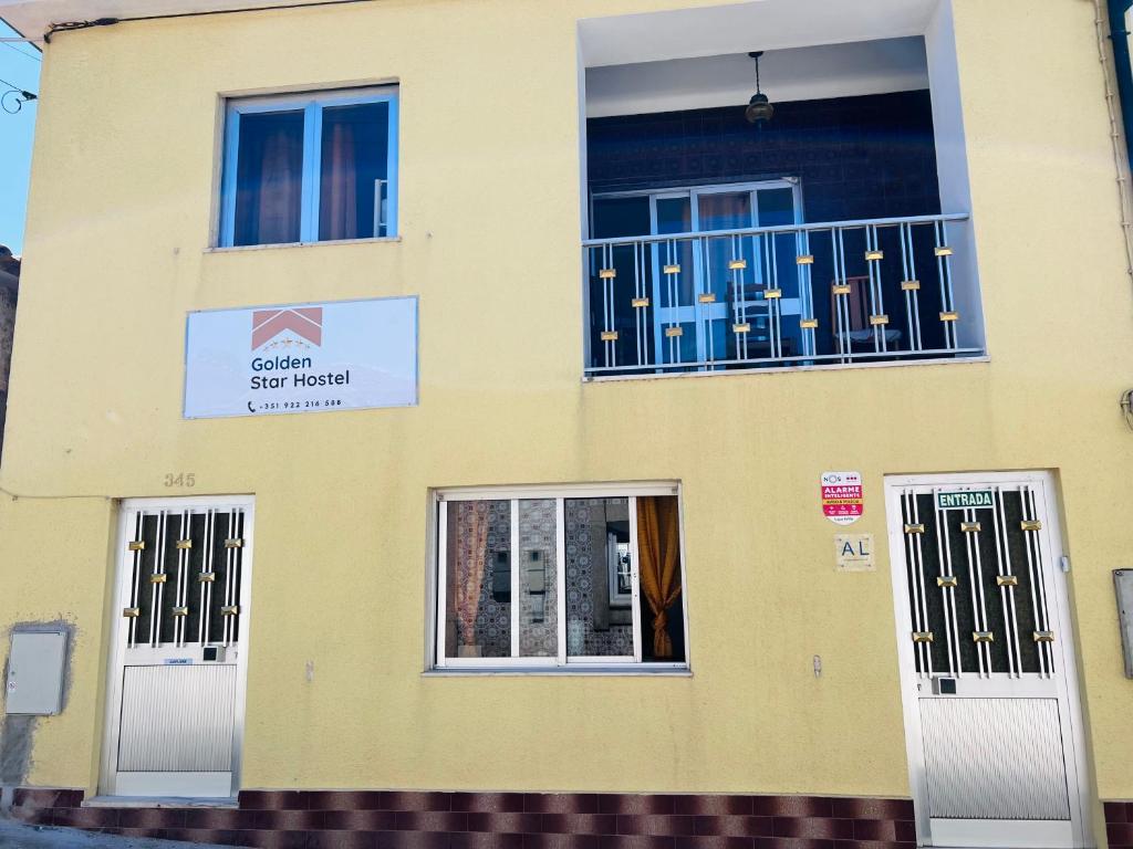 Edificio amarillo con 3 ventanas y balcón en G & S - Hostel Vila do Conde, en Gião