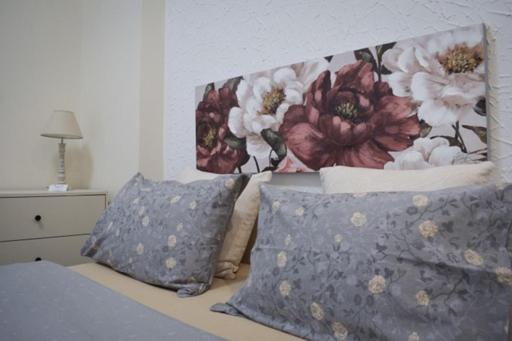 een bed met 2 kussens en een hoofdeinde met bloemen bij Domenica studios 1 in Thessaloniki