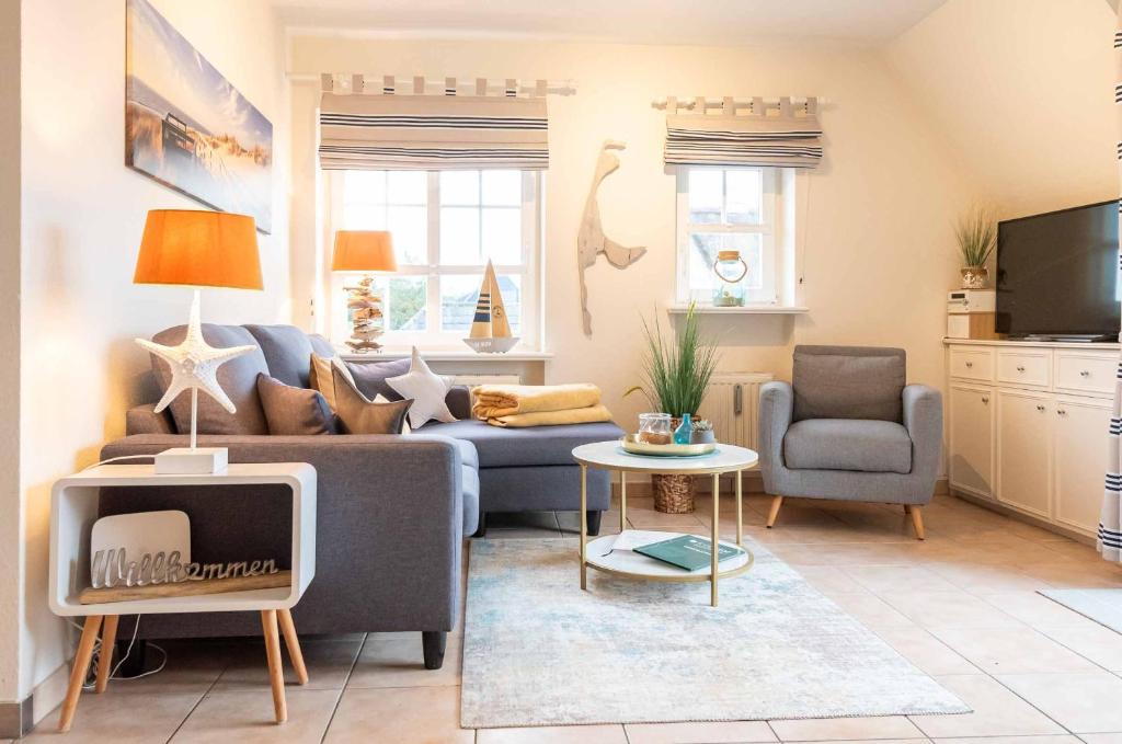 a living room with a blue couch and a tv at SyltStern Haus Hasenkuhle in Wenningstedt