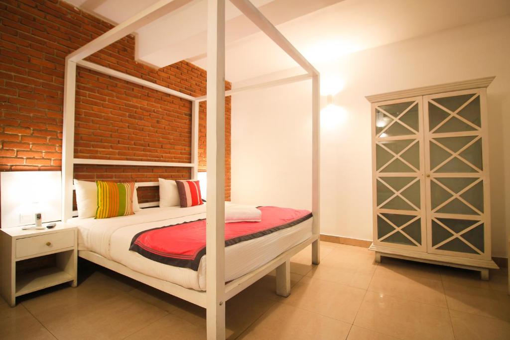 a bedroom with a canopy bed and a brick wall at Clock Inn Dehiwala in Mount Lavinia